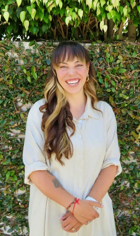 Bryce Ezrre in a cream linen shirt, full-length portrait against ivy